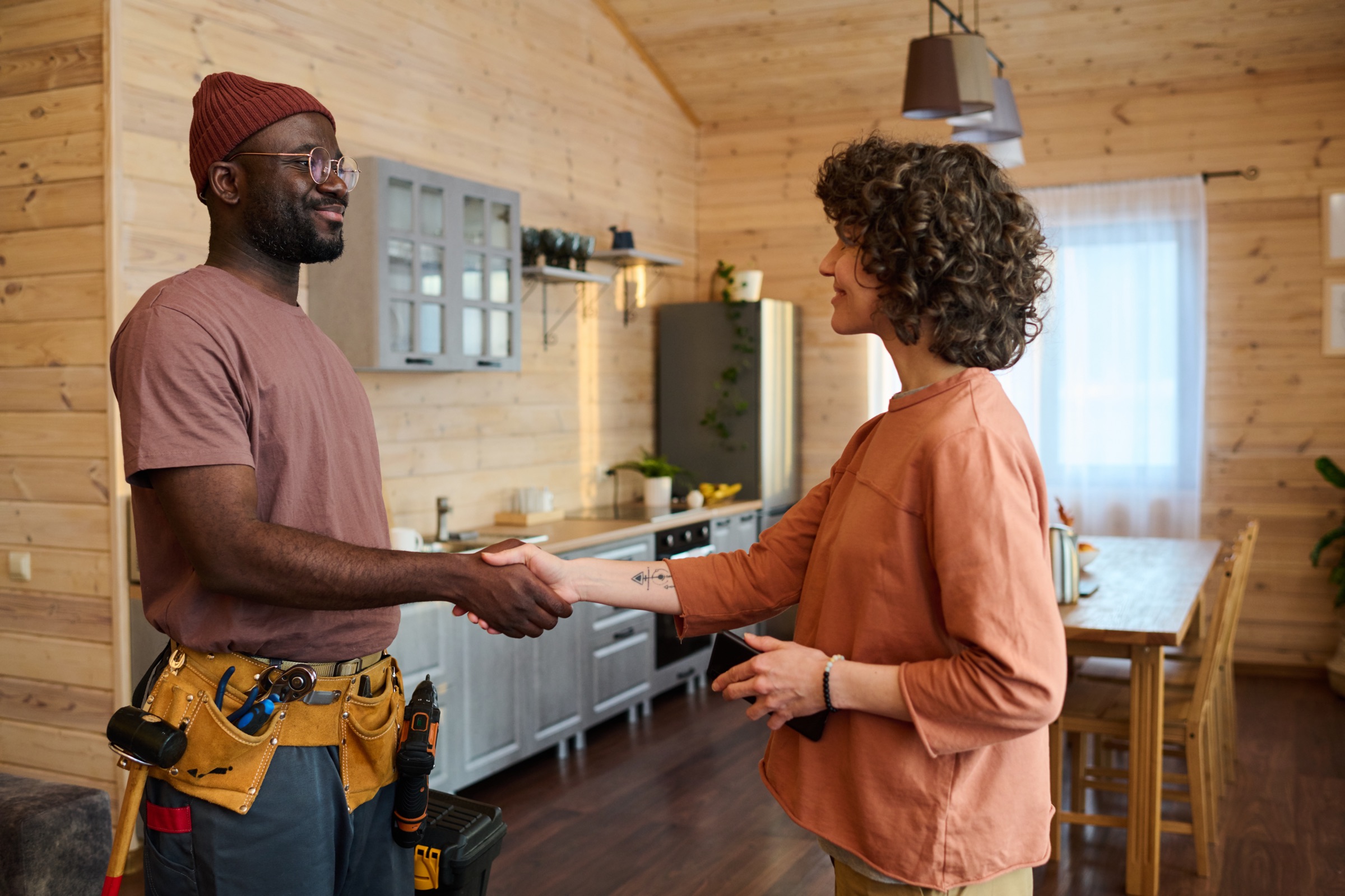 A contractor shaking hands with a client in her kitchen